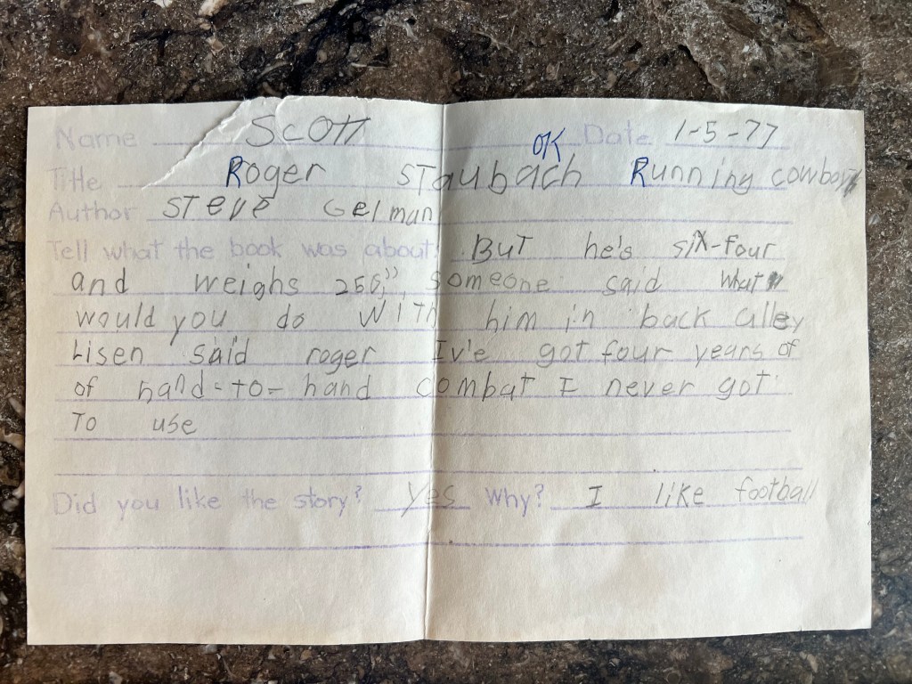 A handwritten book report about Roger Staubach by a student named Scott, dated 1-5-77. The report includes details about the book's content and a personal opinion on the story.